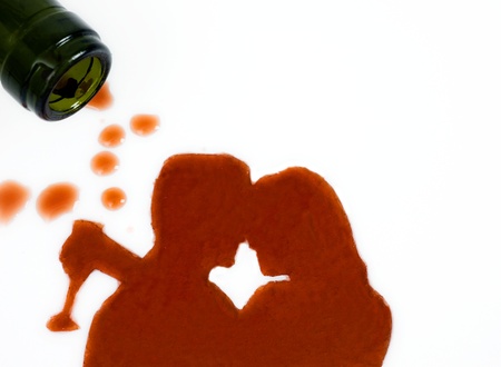 wine bottle on the side with spilled wine in shape of kissing man and woman silhouette.  
の写真素材