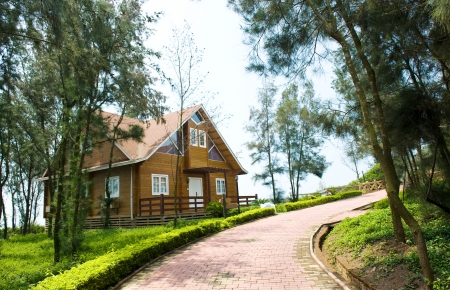 A wooden house beside curving lane and surrounded by many trees.のeditorial素材