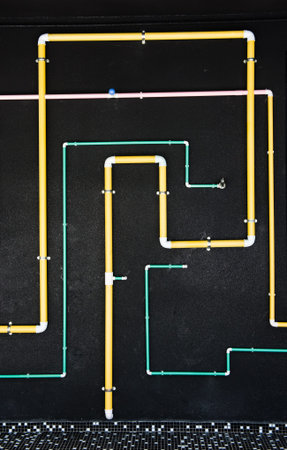 Colorful pipeline on black wall of a building.