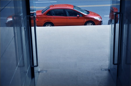 red car park street in front of doorway.