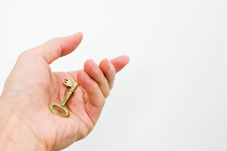 Hand holding a key of success over a white background