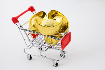 shopping cart full of Chinese gold ingot ornaments isolated on white. の写真素材