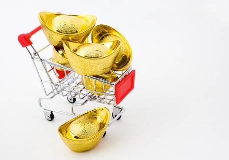shopping cart full of Chinese gold ingot ornaments isolated on white. の写真素材