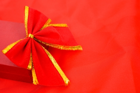 A red ribon tied in a bow over a box isolated on red background. 
の写真素材