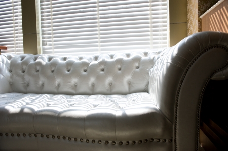 Modern white sofa near the windows, with sunshine come from the blinds. 
の写真素材