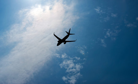 Airplane is flying in the sky among dark and bright clouds.の写真素材