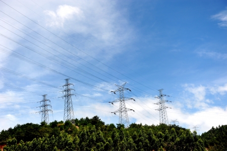 Power lines and electric pylons in a mountain with the blue sky background.の写真素材