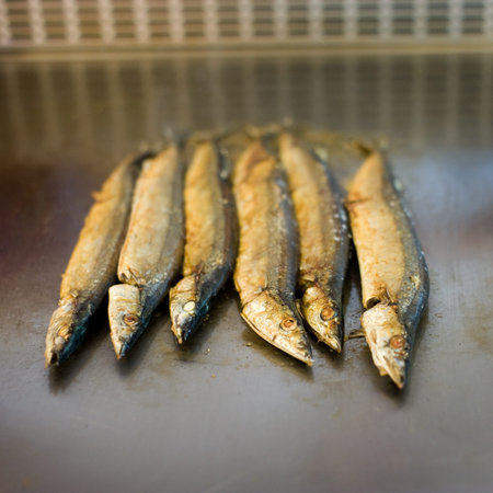 Japanese chef cooking traditional saury teppanyaki on a hot plate. 