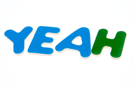 Wooden letters spelling the word  YEAH  on white background. 