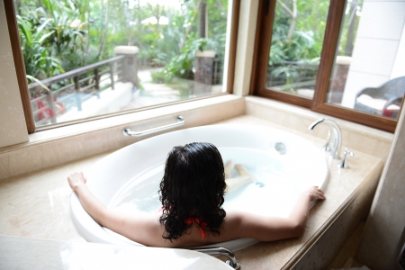 young woman in bathtub with a beautiful view outside the window の写真素材