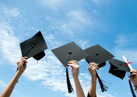 Many hand holding graduation hats on background of blue sky. の写真素材