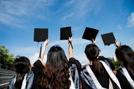 Many hand holding graduation hats on background of blue sky. の写真素材
