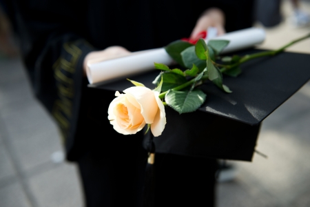 people in a gown holding a diploma and rose.の写真素材