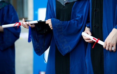 people in a gown holding a diploma.の写真素材