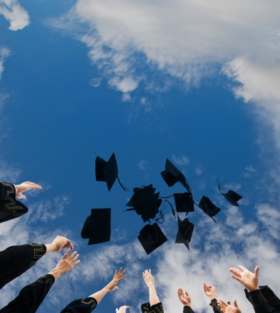 high school graduates tossing up hats over blue sky. の写真素材
