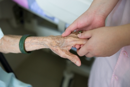 Young girl's hand touches and holds an old woman's wrinkled hands.の写真素材