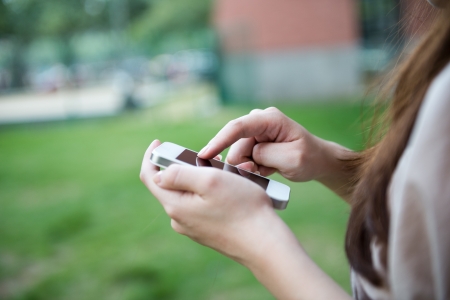Close up of woman using mobile smart phone in the park.の写真素材