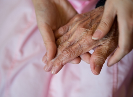 Young girl's hand touches and holds an old woman's wrinkled hands.の写真素材