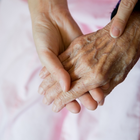 Young girl's hand touches and holds an old woman's wrinkled hands.の写真素材