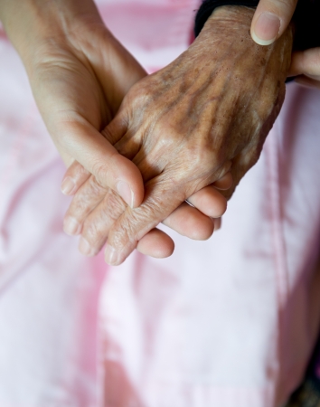 Young girl's hand touches and holds an old woman's wrinkled hands.の写真素材