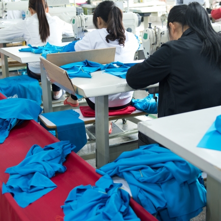 Industrial size textile factory in asia, asian workers behind sewing machines.のeditorial素材