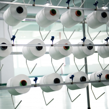 Textile industry - yarn spools on spinning machine in a textile factoryの写真素材