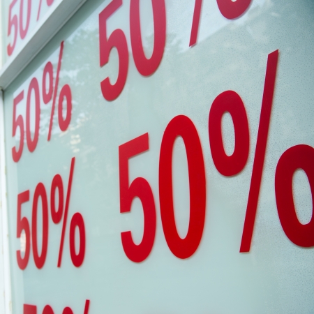 Red sale signs on shop wall, big reductions.の写真素材