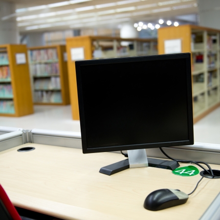 computer in a library with many books and shelves in the background.の写真素材