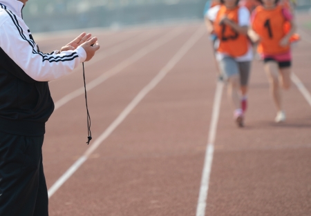Close-up of a man holding a stopwatch to measure performances of the runners in a stadium
の写真素材