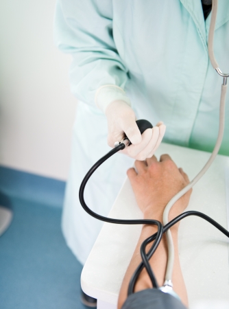 Doctor measuring blood pressure of patient at medical consultation.の写真素材