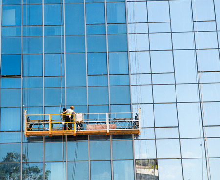 Workers of steeplejack washing windows of the modern building.の写真素材