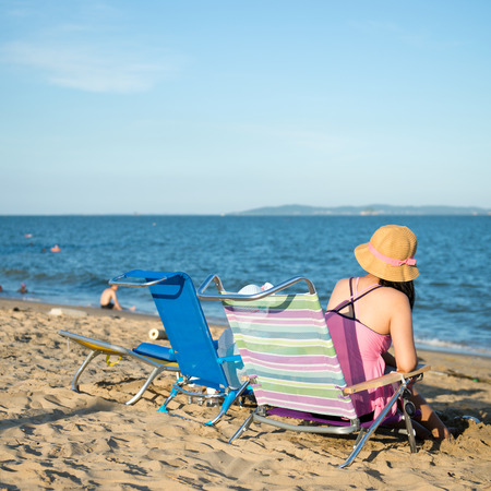 Young mother with baby daughter sitting in front of the sea.の写真素材