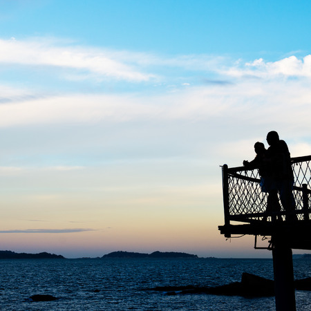Man and woman enjoying the sea together at sunset.の写真素材