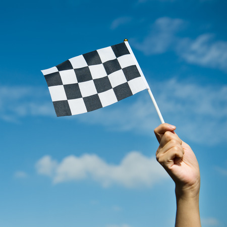 checkered race flag in hand.の写真素材