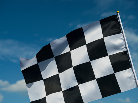 checkered race flag waving on blue sky.の写真素材