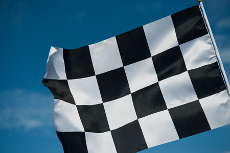 checkered race flag waving on blue sky.の写真素材