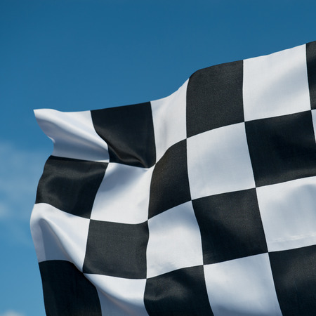 checkered race flag waving on blue sky.の写真素材
