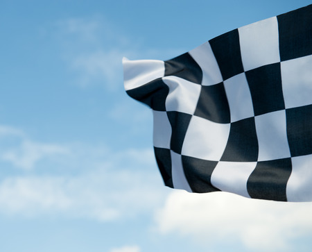 checkered race flag waving on blue sky.の写真素材