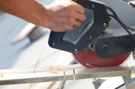 Carpenter cutting wood by electric saw.の写真素材