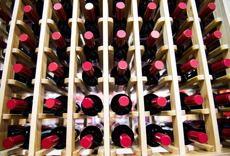 Group of red wine bottles stacked on wooden racks.の写真素材