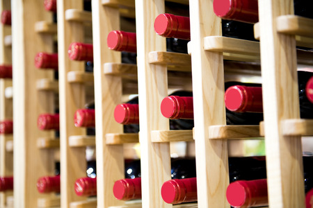Group of red wine bottles stacked on wooden racks.の写真素材