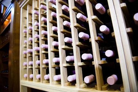 Group of red wine bottles stacked on wooden racks.の写真素材