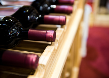 Group of red wine bottles stacked on wooden racks.の写真素材