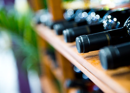 Group of red wine bottles stacked on wooden racks.