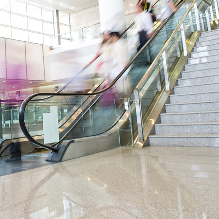 Group of businesspeople moving down on escalator in office. blurred motion.のeditorial素材