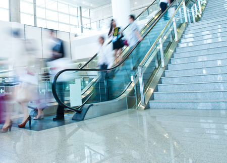 Group of businesspeople moving down on escalator in office. blurred motion.のeditorial素材