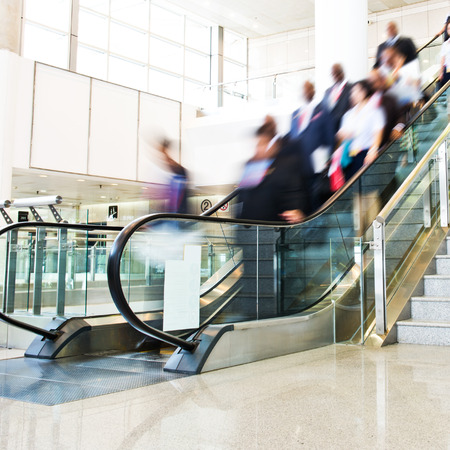 Group of businesspeople moving down on escalator in office. blurred motion.のeditorial素材