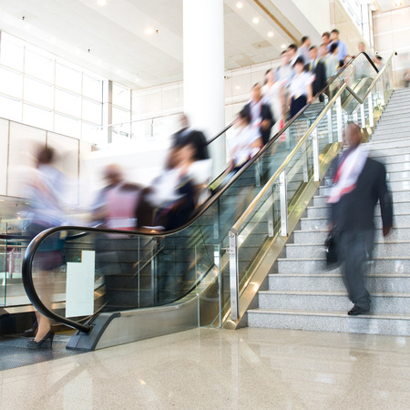 Group of businesspeople moving down on escalator in office. blurred motion.のeditorial素材