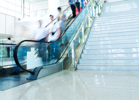 Group of businesspeople moving down on escalator in office. blurred motion.のeditorial素材
