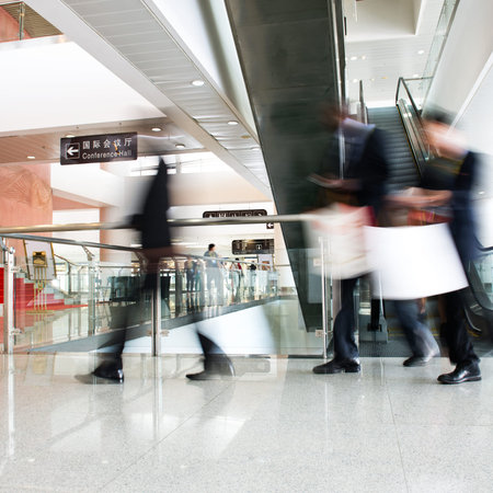 Group of businesspeople moving down on escalator in office. blurred motion.のeditorial素材